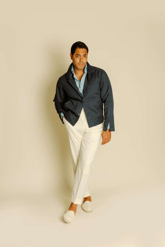 Angel Ramos in the Denim Blue Cashmere Blouson, styled with a light blue shirt and white trousers for a relaxed yet sophisticated summer look.