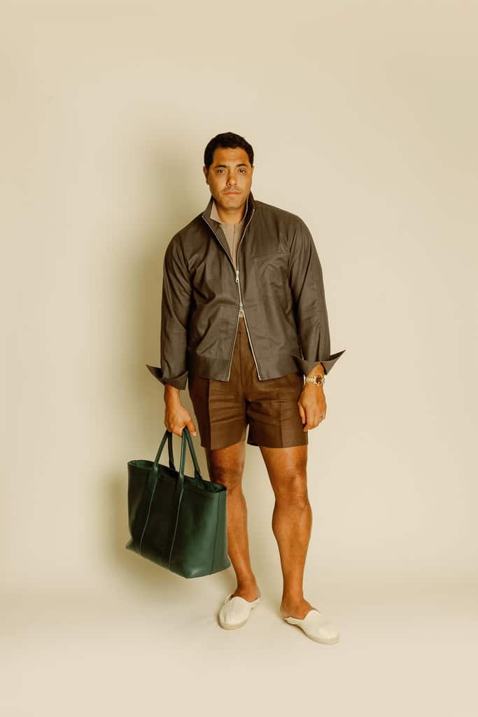 Angel Ramos wearing the Tobacco Brown Summer Cashmere Jacket, paired with matching tailored shorts and a green leather tote, embodying refined summer style.