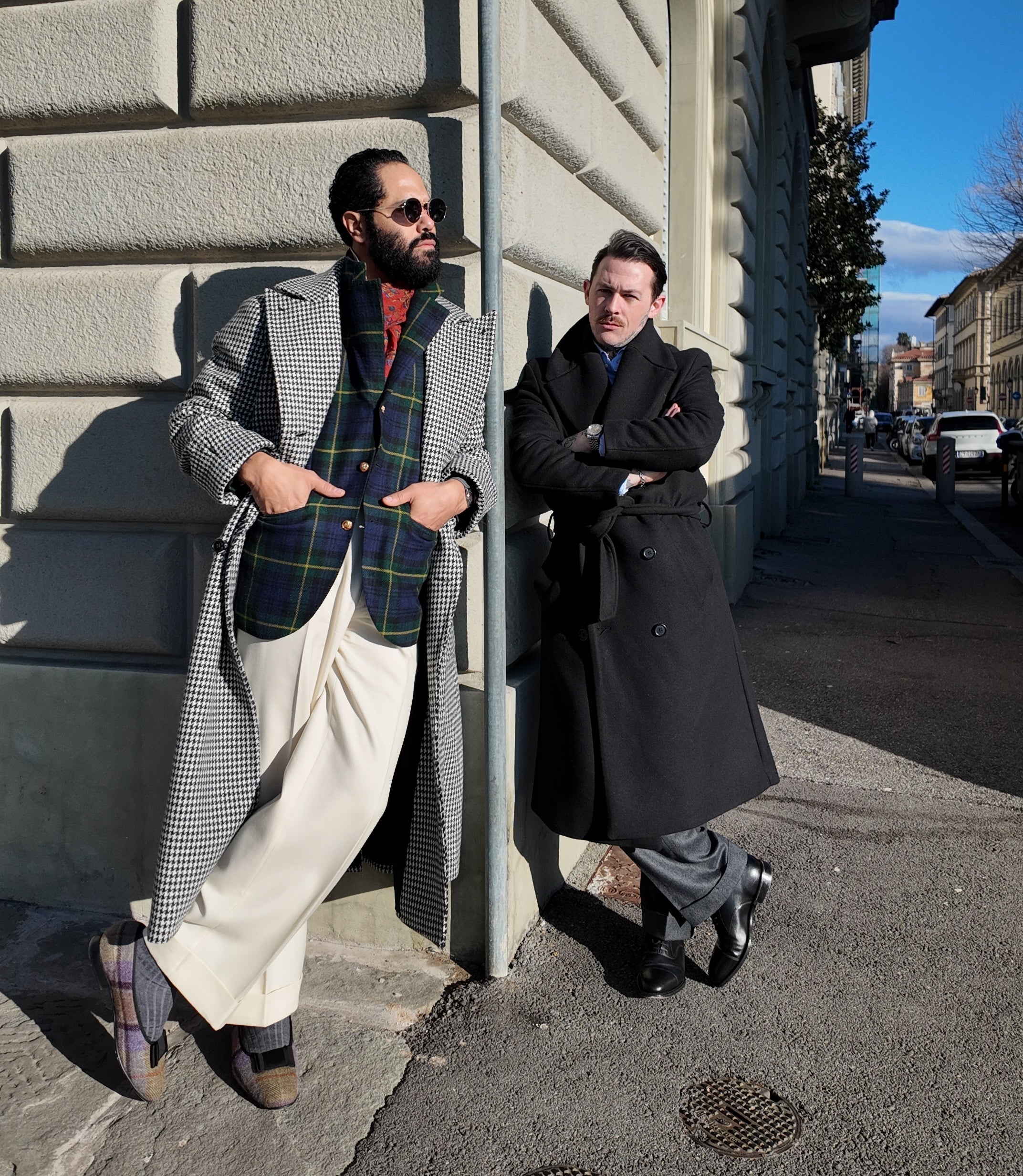 Angel Ramos and Damien Broderick leaning against a wall on a city street.